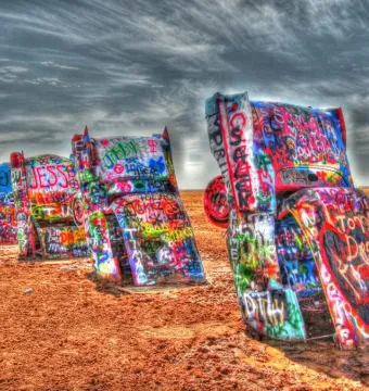 Cadillac Ranch with several vintage car bodies buried nose-down and covered in colorful graffiti.