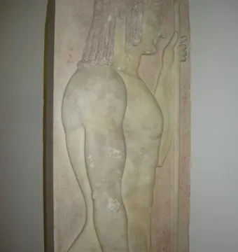 Grave stele with a carved male figure in profile facing right, holding a staff and showing traces of red pigment.