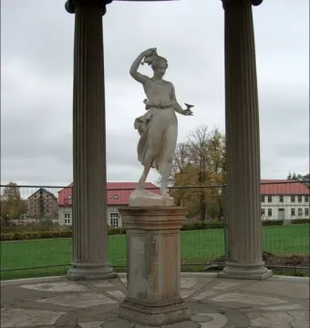 Classical statue of Hebe holding a jug and cup between two fluted columns.