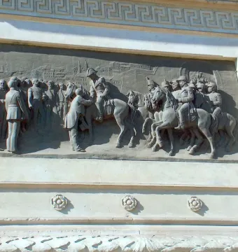 Bronze low-relief panel on the Marqués del Duero monument showing horsemen and standing figures before a cityscape.
