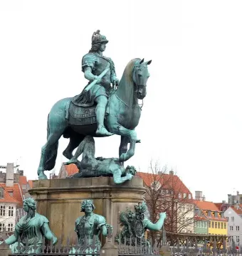 Christian V equestrian statue showing an armored rider on a rearing horse atop an ornate pedestal with sculptural figures.