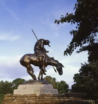 End of the Trail bronze statue of a bowed rider on a horse atop a stone pedestal.