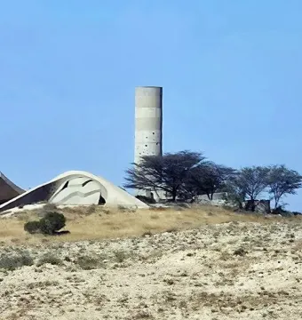 The Monument to the Negev Brigade, with a tall cylindrical concrete tower and sculptural low concrete forms on a barren hill.