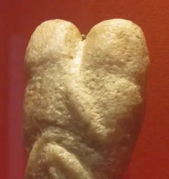 Ain Sakhri Lovers stone figurine with two rounded forms on top and a tapering, intertwined lower section.