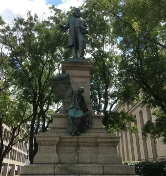 Albert Pike Memorial with a standing bronze figure on a tall pedestal and a seated draped figure below it