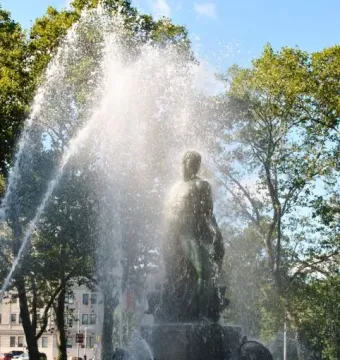 Bailey Fountain with a dark statue standing amid cascading water and mist.