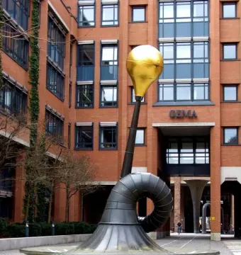 Erich-Schulze-Brunnen sculpture with a coiled metal tube and golden sphere in a plaza