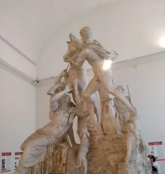 The Farnese Bull marble sculpture showing a bull held by two male figures, with a distressed draped woman at the base and a small dog nearby.