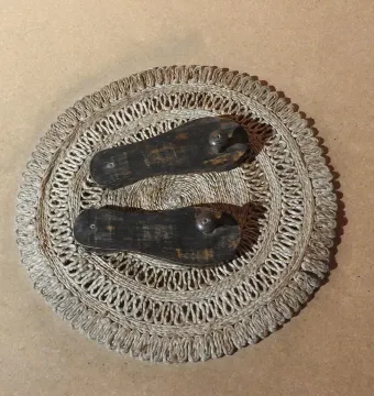 Paduka wooden sandals displayed on a woven mat.