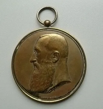 Bronze-toned medallion with the profile of Leopold II facing left and a hanging loop at the top.