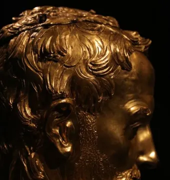 Saint Rossore Reliquary gilded bust in profile, showing curly hair, beard, and mustache.