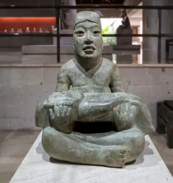 Las Limas Figurine showing a seated stone figure holding a smaller jaguar-like figure across its lap.