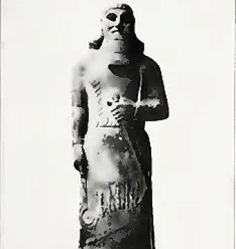 Statue of Ashurnasirpal II standing on a rectangular base, with a long carved garment and prominent beard.