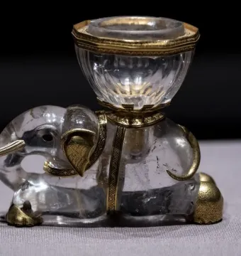 Crystal elephant with gold-colored details carrying a faceted crystal salt cellar on its back.