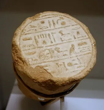 Circular end of a funerary cone with deeply incised ancient Egyptian hieroglyphs in horizontal lines.