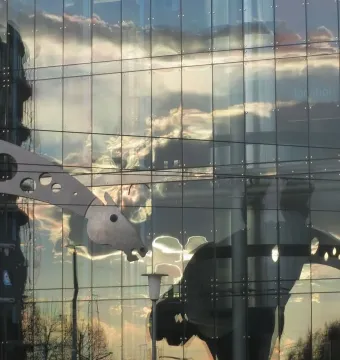 S-Printing Horse sculpture reflected in a glass building at sunset