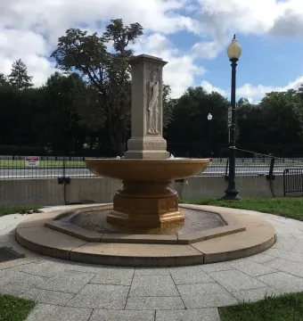 Butt-Millet Memorial Fountain with a stone figure on a central pillar and water flowing into a circular basin.