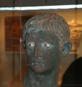Meroë Head bronze sculpture with a weathered green patina and inlaid eyes.