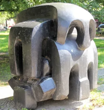 Treblinka abstract sculpture with blocky dark forms and carved openings in a paved outdoor setting.