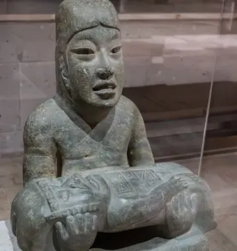Las Limas Figurine showing a seated stone figure holding a smaller figure across its lap.