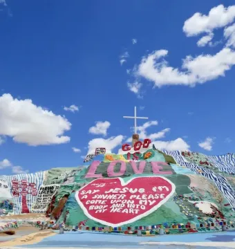 Salvation Mountain with colorful painted patterns, a red heart, the words “God Is Love,” and a white cross at the top.