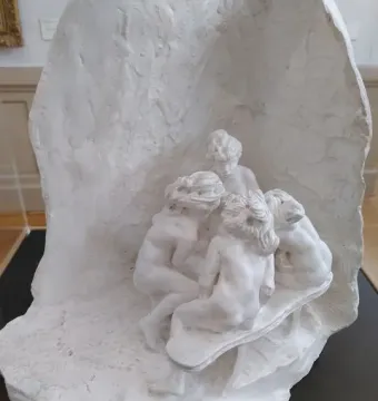 The Confidence, a white plaster sculpture of four closely gathered figures inside a cave-like enclosure.