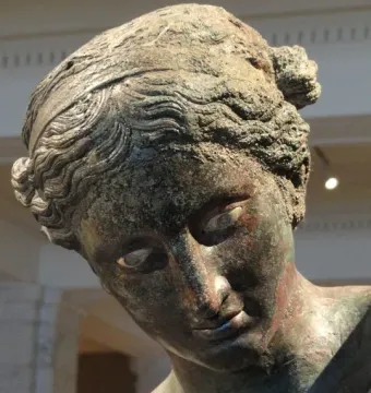 Close-up of The Cleveland Apollo’s bronze head with a greenish-brown patina and downward gaze.