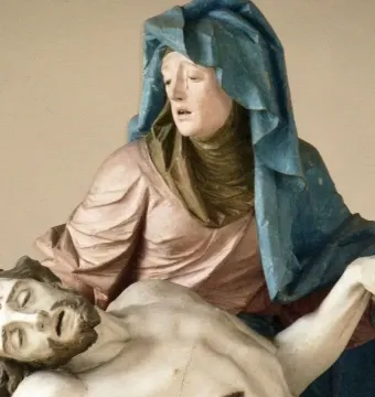 Close-up of the Nenningen Pietà showing a polychrome figure in a blue cloak supporting a lifeless bearded figure.