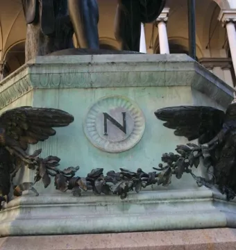 Bronze base of Napoleon as Mars the Peacemaker with two eagles and an N emblem, beneath the lower figure and in front of classical architecture.