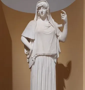 Giustiniani Hestia, a white marble statue of a veiled female figure in a long pleated gown, standing with one hand on her hip and the other raised.