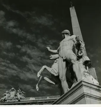 The Horse Tamers sculpture seen from behind, with a rearing horse and an obelisk rising in the background.