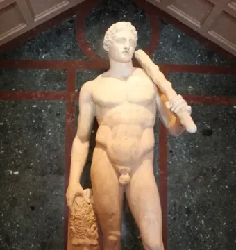 Lansdowne Heracles statue holding a club over his shoulder beside a lion skin, standing on a dark base.