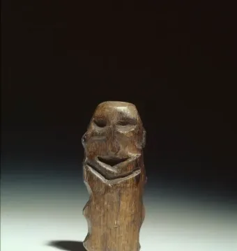 Mannetje van Willemstad wooden idol with carved facial features on a dark brown vertical sculpture.