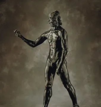 Bronze sculpture of Saint John the Baptist, a muscular bearded male figure standing with one arm outstretched.