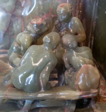Close-up of The Confidence showing four closely grouped carved figures in polished green stone.