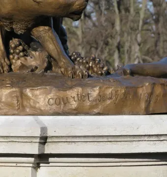 Close-up of the base of the Centauress and Faun sculpture, showing foliage, grapes, and the inscription \