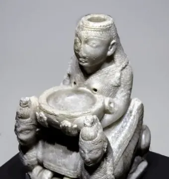 Lady of Galera figurine showing a seated stone figure holding a shallow bowl, flanked by two smaller winged figures.