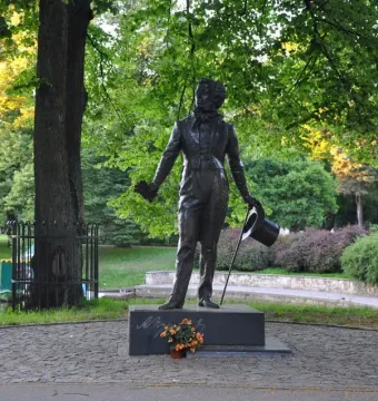 Pushkin statue in a park beside a body of water, with trees and paddle boats in the background.
