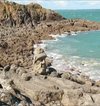 Rothéneuf Sculpted Rocks showing carved figures in granite along the rocky coast, with a prominent bust and reclining figure in the foreground.