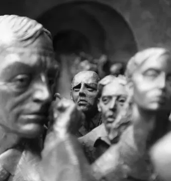 Close-up of bronze-like sculpted figures in The Meeting Place, including a man in a suit and tie in the foreground.