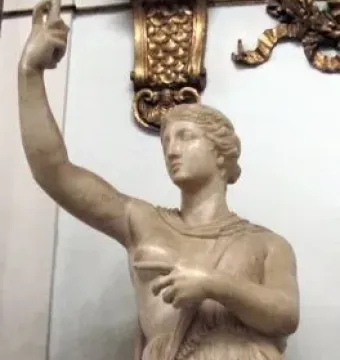 Marble statue of a wounded Amazon standing with one arm raised and a short tunic.
