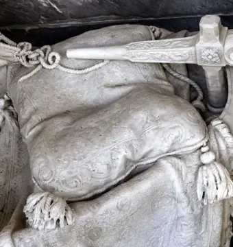 Close-up of Angelo Nocchiero showing carved draped stone fabric, ropes, tassels, and an ornate ship-like handle.
