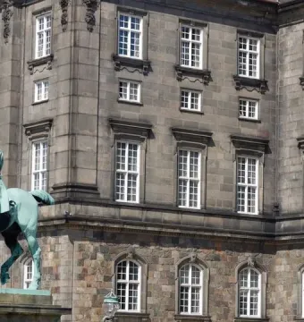 Christian IX equestrian statue in front of a large stone building with many windows.