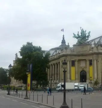 The Immortality Overtaking Time sculpture atop the Grand Palais in Paris, with its glass dome, street, and plaza below.