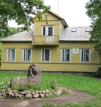 Recumbent lion statue in a flower bed beside a yellow building in Monrepos Park