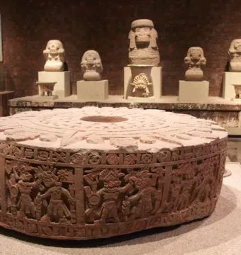 Stone of Motecuhzoma I with detailed carvings, circular frieze figures, and a central depression on top.