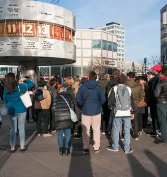 The World Clock stands in a public square with people gathered around its base.