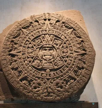 The Aztec Sun Stone, a large circular carved stone disc with a central face and concentric rings of symbols and figures.