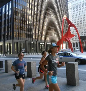 Flamingo red abstract sculpture in an urban plaza with tall glass buildings behind it