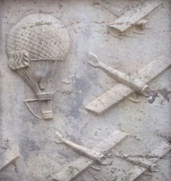 Stone relief from Flygarmonumentet showing a hot air balloon and several propeller airplanes in flight.